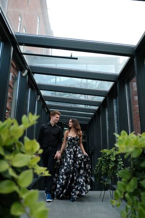 Young beautiful couple - a girl in a magnificent dress and a guy in a black shirt and trousers are...