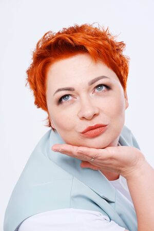 Studio portrait of surprised red-haired woman age 35-40 years on plain background. Human emotionsの写真素材