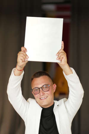 A young man of 30-35 years old in a white jacket, black turtleneck, glasses and a short haircut...