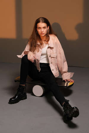 Portrait of a young beautiful girl 20-25 years old with green eyes and long hair. Girl sitting on a balance board and posing. Fashion photography conceptの写真素材