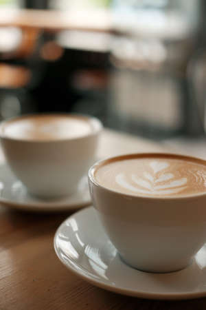 Beautiful white mug with cappuccino or latte coffee on a wooden table. View from above. Breakfast in the cafe.の写真素材