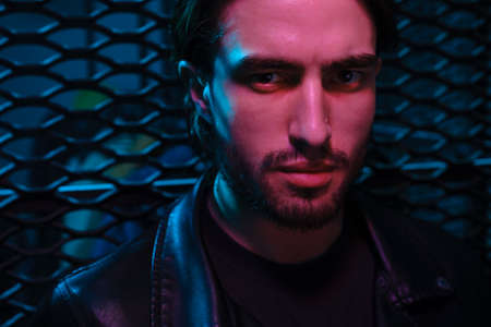 Beautiful caucasian young man portrait isolated on multicolored neon light backgroud. Human emotions, facial expression concept. Trendy colors.Advertising conceptの写真素材