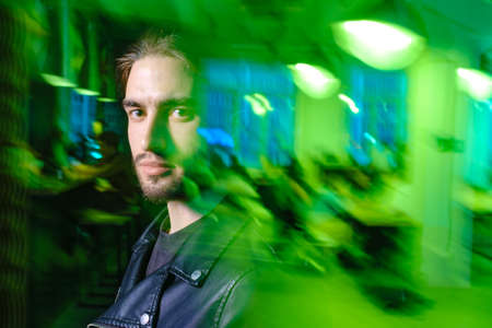Beautiful caucasian young man portrait isolated on green neon light backgroud. Human emotions, facial expression concept. Trendy colors.Advertising conceptの写真素材