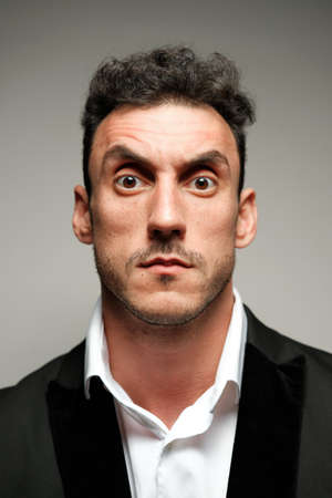 Close up portrait of a man 30-34 years old in a white shirt and a black jacket on a gray background.の写真素材
