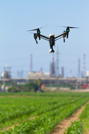 Drone for agriculture is hovering over plantation on the background of a chemical facilityの写真素材