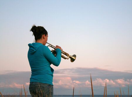 A teenager plays her trombone at the beachの写真素材