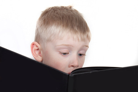Little boy interested in reading a bookの写真素材