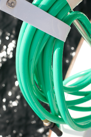 green water hose on a boat with oceanの写真素材