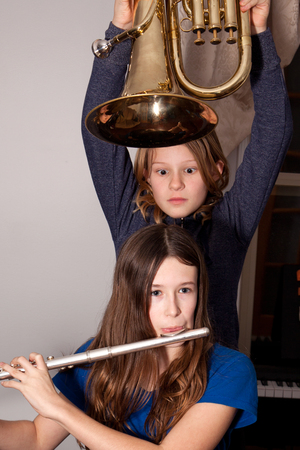 Two young girls fooling around with musical instruments.の写真素材