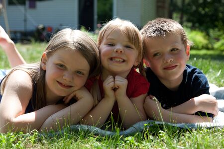 three siblings outside in grass