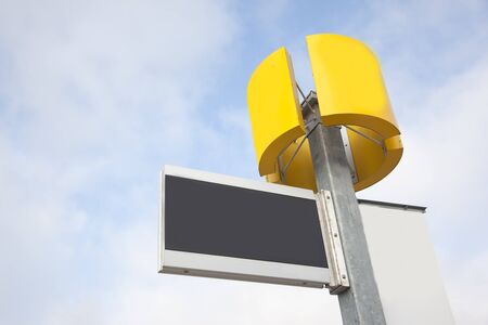 a blank black sign ready for text, with a round yellow space also blank against blue skyの写真素材