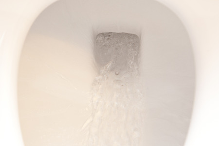 Water swirling down a flushed toiletの写真素材