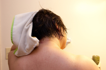 Back of a woman's dark head of hair as she rubs it dry with a towelの写真素材