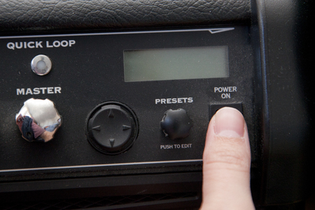 Turning the power switch on a dusty guitar amplifie ready to be played