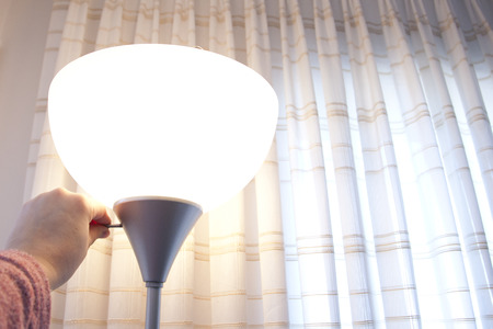 Hand turns the switch on a lampの写真素材