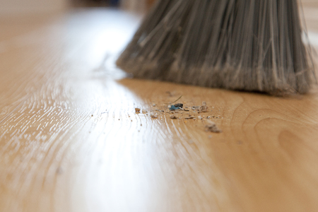 Close up of dirt and sweepings on the floor beside a broomの写真素材