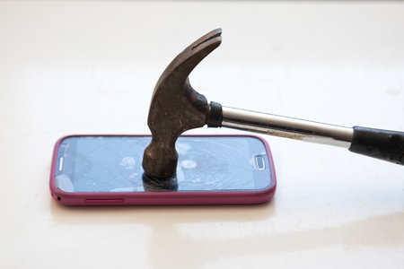 Taking a hammer and smashing a cell phoneの写真素材