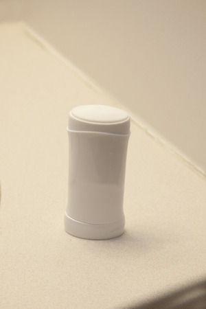 A white stick of deoderant or antiperspirant on the bathroom sink at homeの写真素材