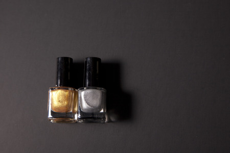 Silver polish and gold nail polish together on black background with copy spaceの写真素材