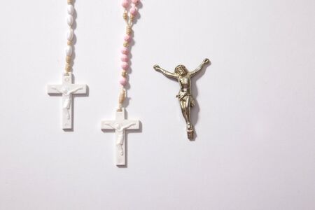 white and pink rosary beads with jesus on the cross and copy space