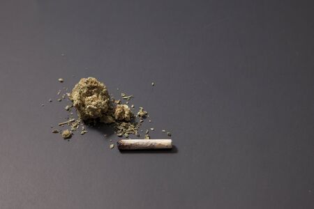 a small amount of pot on a black background and a joint that's already been partly finishedの写真素材