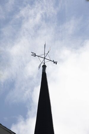 a metal weathervane showing directions on top of a steeple