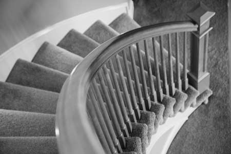 black and white photograph of a beautiful polished wooden railing lining a circular staircase