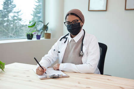 doctor with a hijab stethascope and mask at work in a medical clinicの写真素材