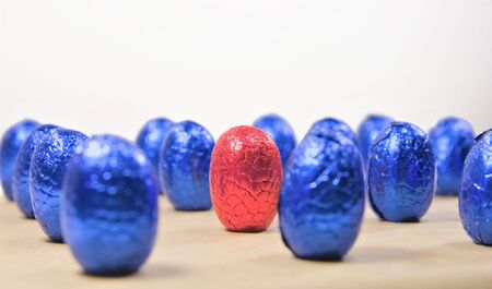 one red easter egg in rows of blue eggsの写真素材