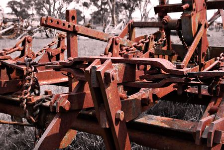 duotone image of an piece of farm equipment rusting away in a fieldの写真素材