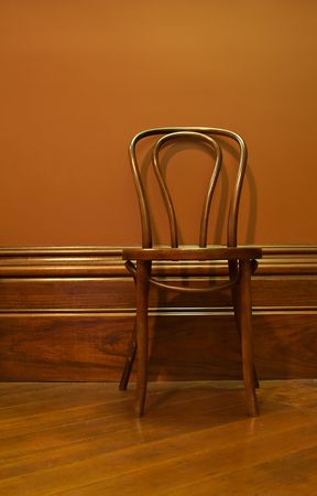 a brown wooden chair against the wall in a brown waiting roomの写真素材