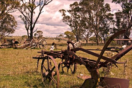 an old rusting horse drawn plow sits in the farm paddock の写真素材