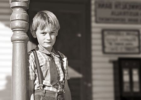 silver gelatin black and white of a young boy in tie and braces stands in front of an old shopの写真素材