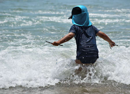 a young boy ventures into the waves at the beachの写真素材