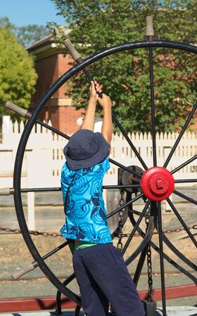 young boy strains to turn an old ships wheelの写真素材