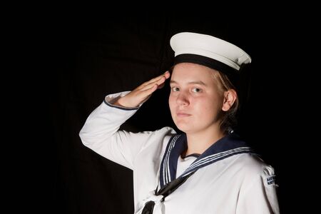 young female navy seaman saluting on blackの写真素材