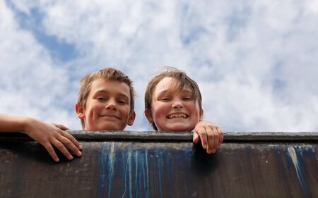 two kids looking over old metal wallの写真素材