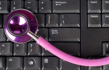 pink stethoscope on a computer keyboardの写真素材
