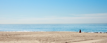 a single woman sits alone on the beach in californiaの写真素材
