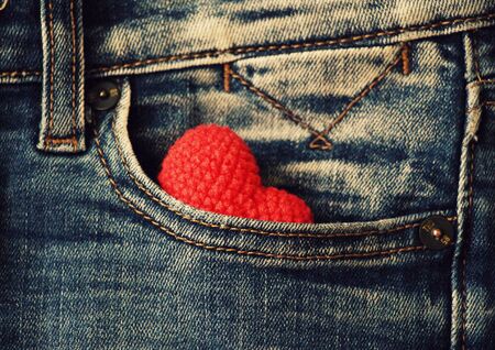 Knitted red heart lies in a jeans pocket.の写真素材