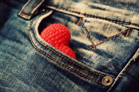 Knitted red heart lies in a jeans pocket.の写真素材