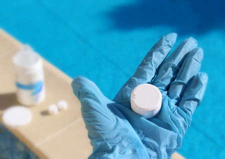 White mini chlorine tablet in the hand of a service worker for disinfection of swimming pools.の写真素材
