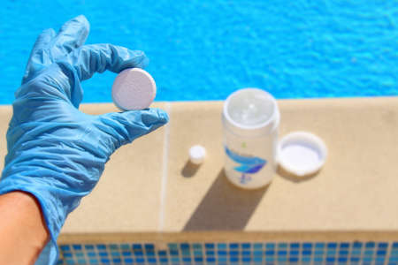 White mini chlorine tablet in the hand of a service worker for disinfection of swimming pools.の写真素材