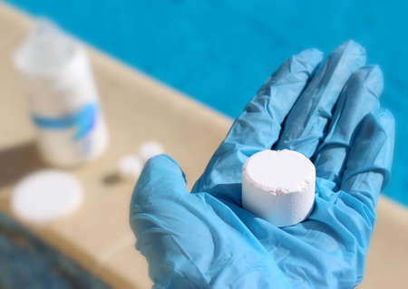 White mini chlorine tablet in the hand of a service worker for disinfection of swimming pools.の写真素材