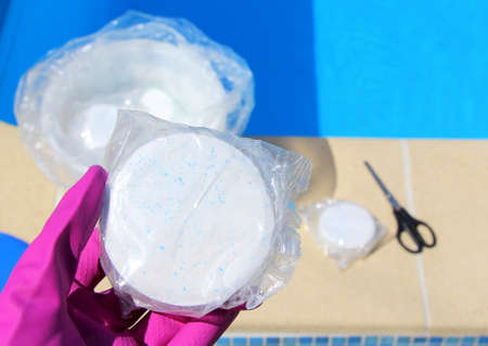 White big chlorine tablet in the hand of a service worker for disinfection of swimming pools. The beginning of the swimming season is hot summer.の写真素材