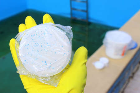 White chlorine tablet in the hand of maintenance personnel for disinfection of swimming pools. Water...