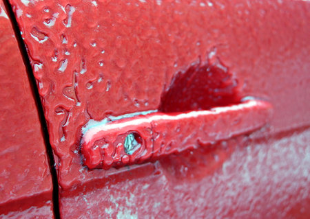 The red car is covered with ice. Icy surface of the car.の写真素材