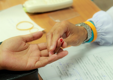 Nurse collects blood specimen from a fingerの写真素材