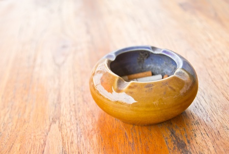 An ashtray filled with smoked cigarettes on a wooden tableの写真素材