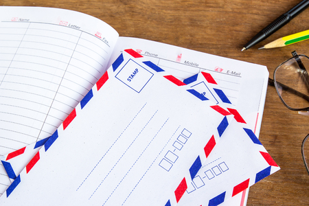 White vintage envelope, pencils, notebook and glasses on a wood floorの写真素材